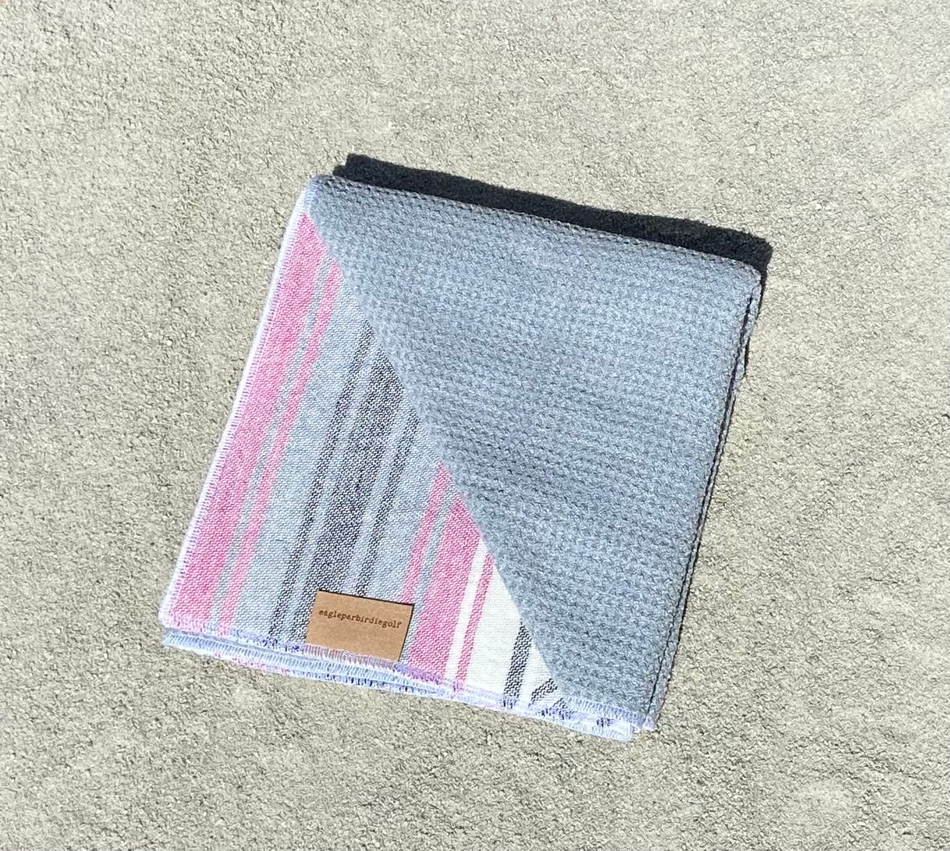 Pink Baja Surf Golf Towel with Gray Interior on Sand