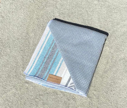 Folded Teal Baja Surf Golf Towel with Gray Interior on Sand