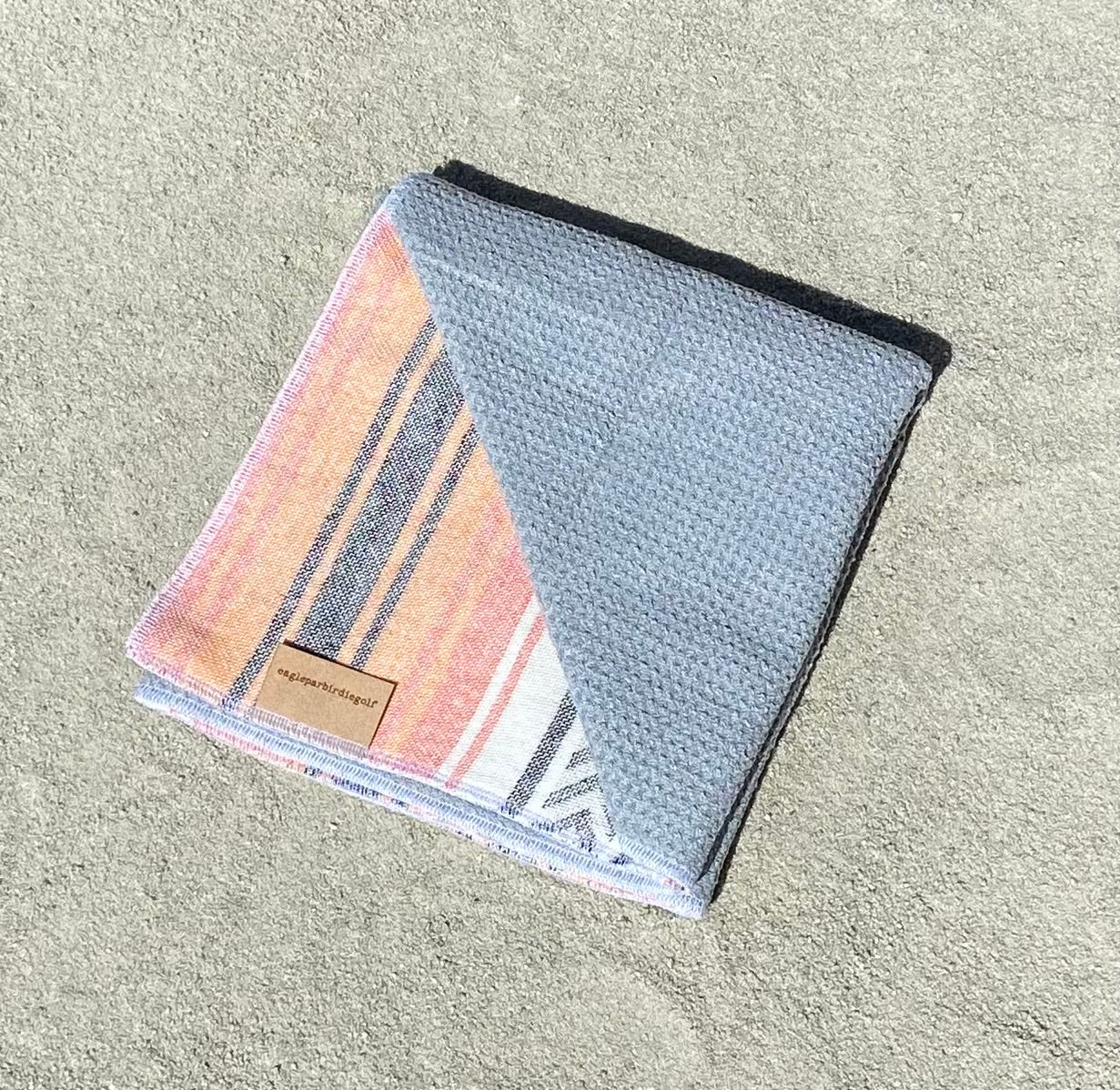 Orange Baja Surf Golf Towel with Gray Interior on Sand